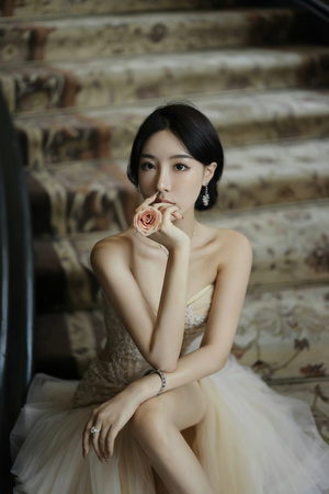 美丽年轻女子坐在台阶上 身着玫瑰花裙 为拍照做姿势。