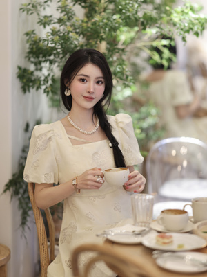 一位穿着白色连衣裙的年轻女子拿着一杯茶或咖啡