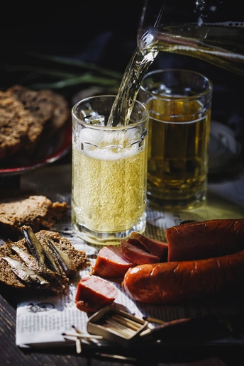 一张带有面包盘、啤酒杯和热狗及其他食物的盘子。