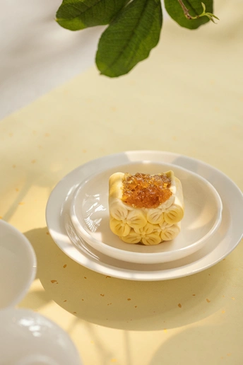 一小盘白盘子上有些意大利面和酱汁 放在一张白色桌子旁边 旁边放着一杯白色杯子。