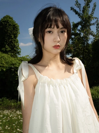 一位留着蓝色头发的年轻女子穿着一件白色衬衫站在一个田野中。