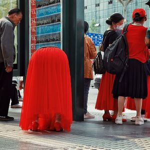 一位穿着红裙子的女士和一位穿着红裙子的男士走下人行道。