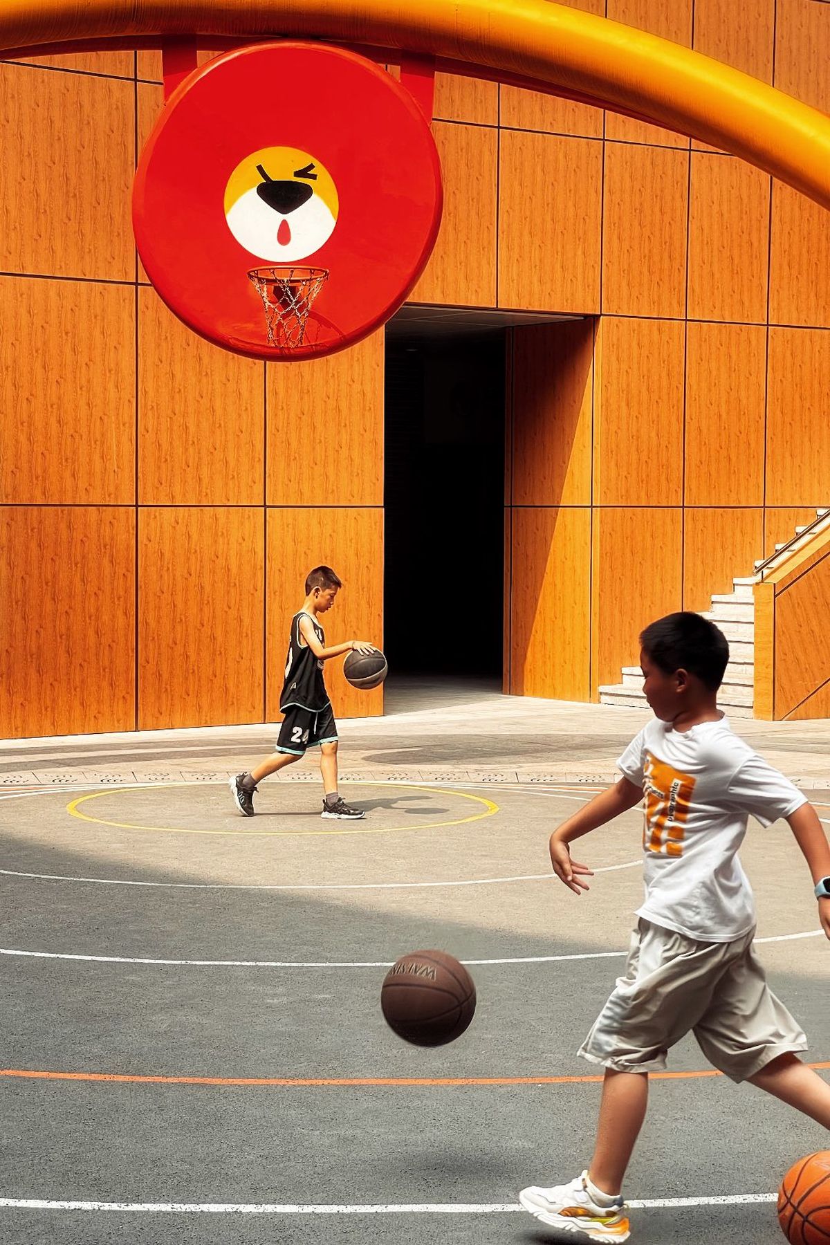 一个年轻男孩和一个年轻男子在场上打篮球。