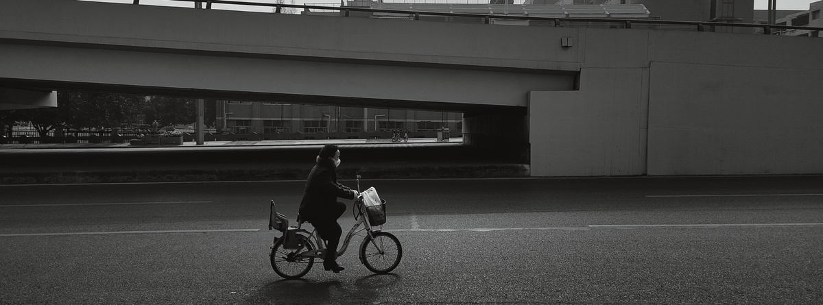 一个人骑着自行车在桥下带着伞