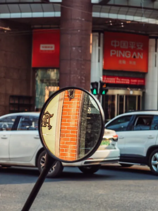 城市街道上的汽车、摩托车和建筑物的反光后视镜