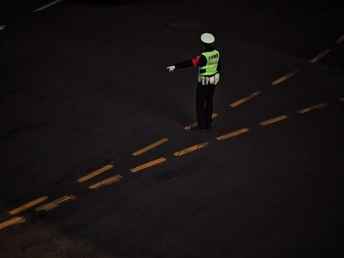 一个穿着霓虹色背心的男子在夜晚的黑暗街道上张开双臂