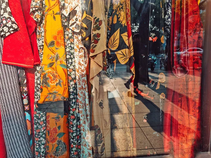 一家有彩色服装和领带挂满衣架的商店的窗户