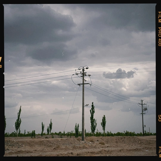 一条有电话线、电力线、树木和交通标志在云天下的道路上