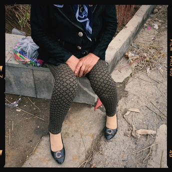 一个穿着黑色紧身裤和黑色鞋子的女人坐在地上