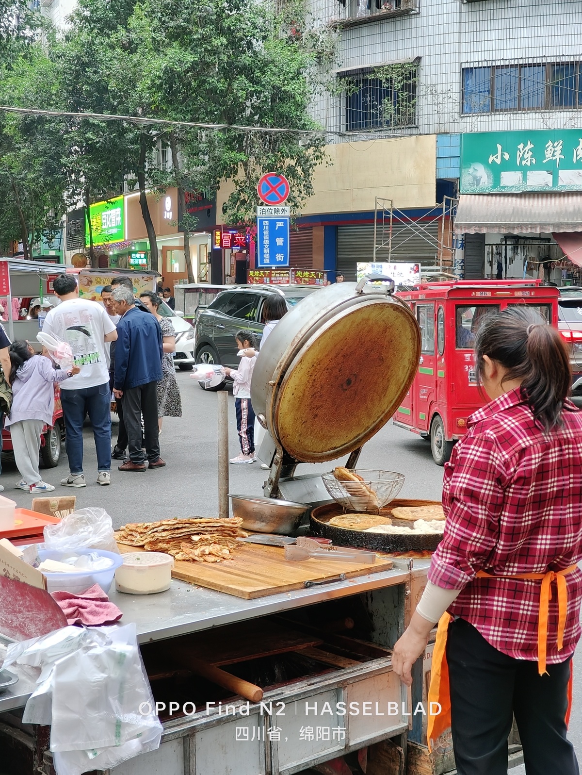一位妇女在街上烹饪食物 周围有人们站着。