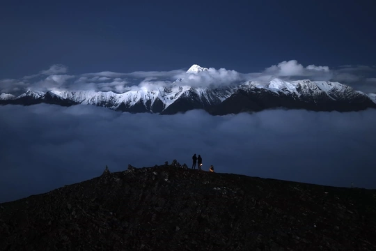 一些人在山顶上站着 看着一个被雪覆盖的山。