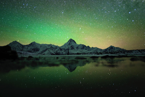 夜晚的山脉 天空中有星星 水面上有绿色的反射。