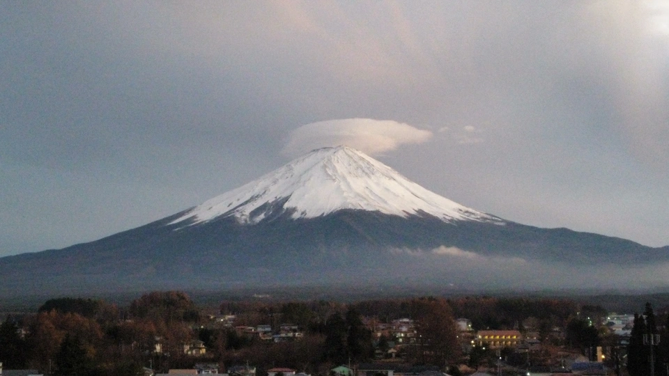 城市后面的一座被雪覆盖的山峰在阳光透过云层时显得格外醒目。