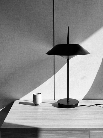 一个黑白相间的灯在桌子上 房间里的墙上有些阴影。