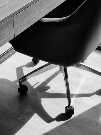 一把黑色办公椅坐在木制桌子旁边