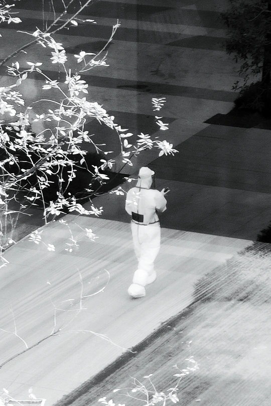 一张黑白照片 一位男士站在人行道上 前方有一扇窗户 手里拿着一把伞。