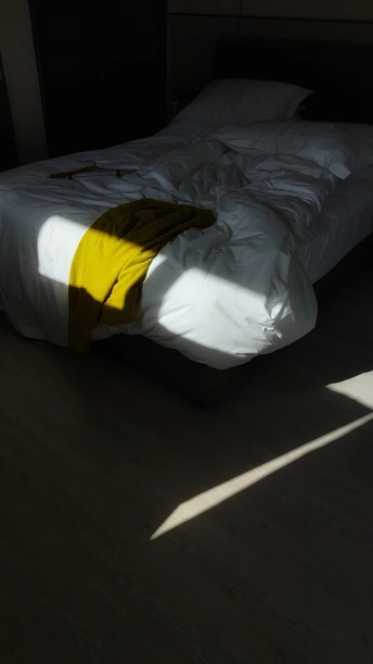 一个带有白色床单和黄色毛毯的黑暗房间