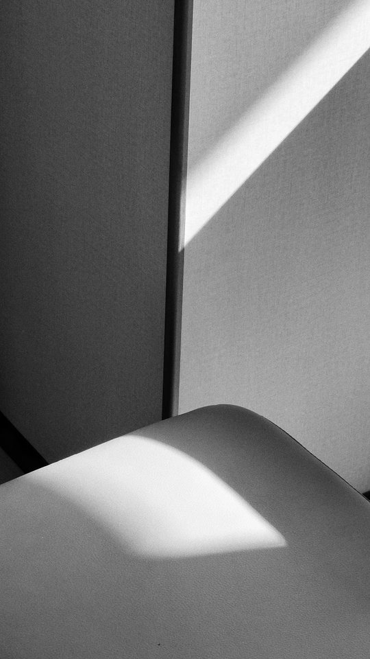 一张坐在床边的白色房间里的椅子 阳光透过窗户照射进来。