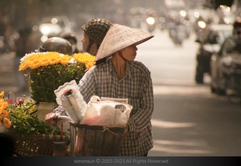 一位戴帽子女士骑自行车带着花篮走下街道
