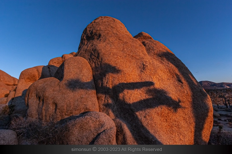 夕阳下的一块大石头 太阳在红色的岩石上投下阴影。