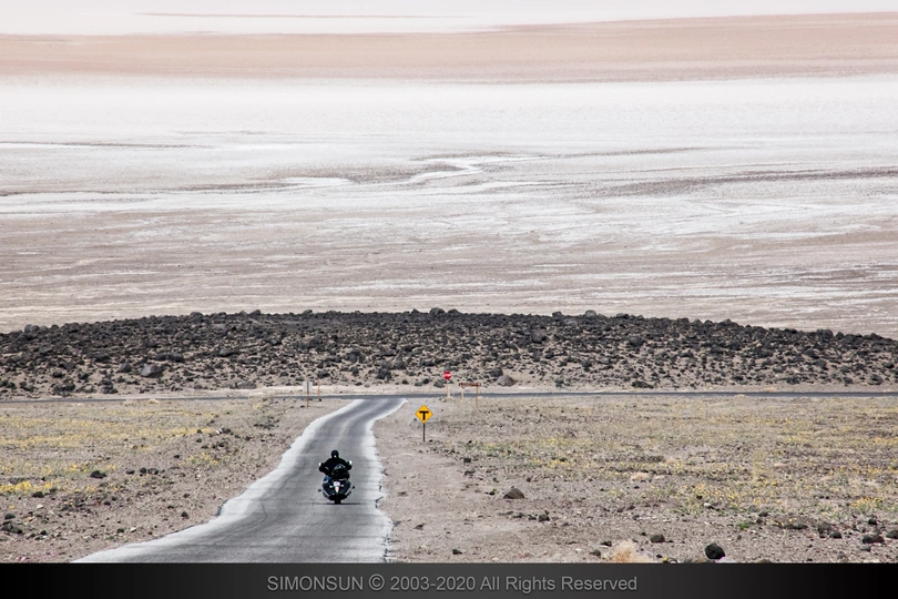 一个人骑摩托车在荒凉的道路上