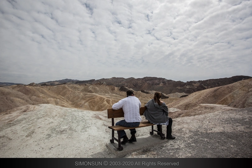 一些人在长凳上坐着 凝视着山丘和山脉的风景。