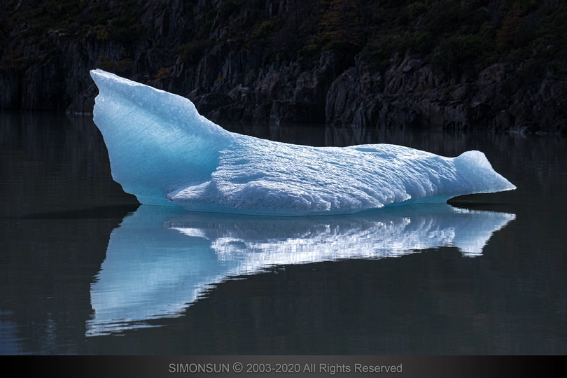 湖上漂浮着一块巨大的冰山 其倒影在水中。