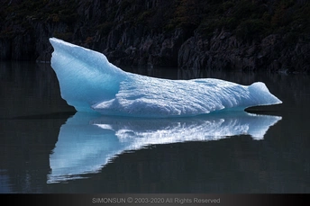 湖上漂浮着一块巨大的冰山 其倒影在水中。