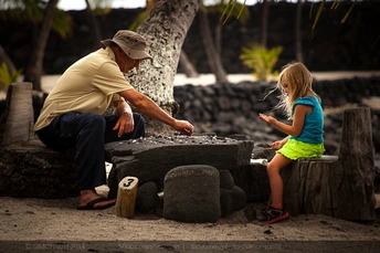 一个男子和一个小女孩坐在沙滩上玩沙子