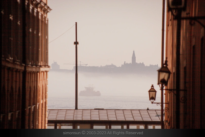 雾气缭绕的城市中有一艘大型船在水中。