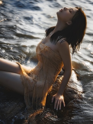 一个穿着漂亮连衣裙的年轻女子坐在海边的水中