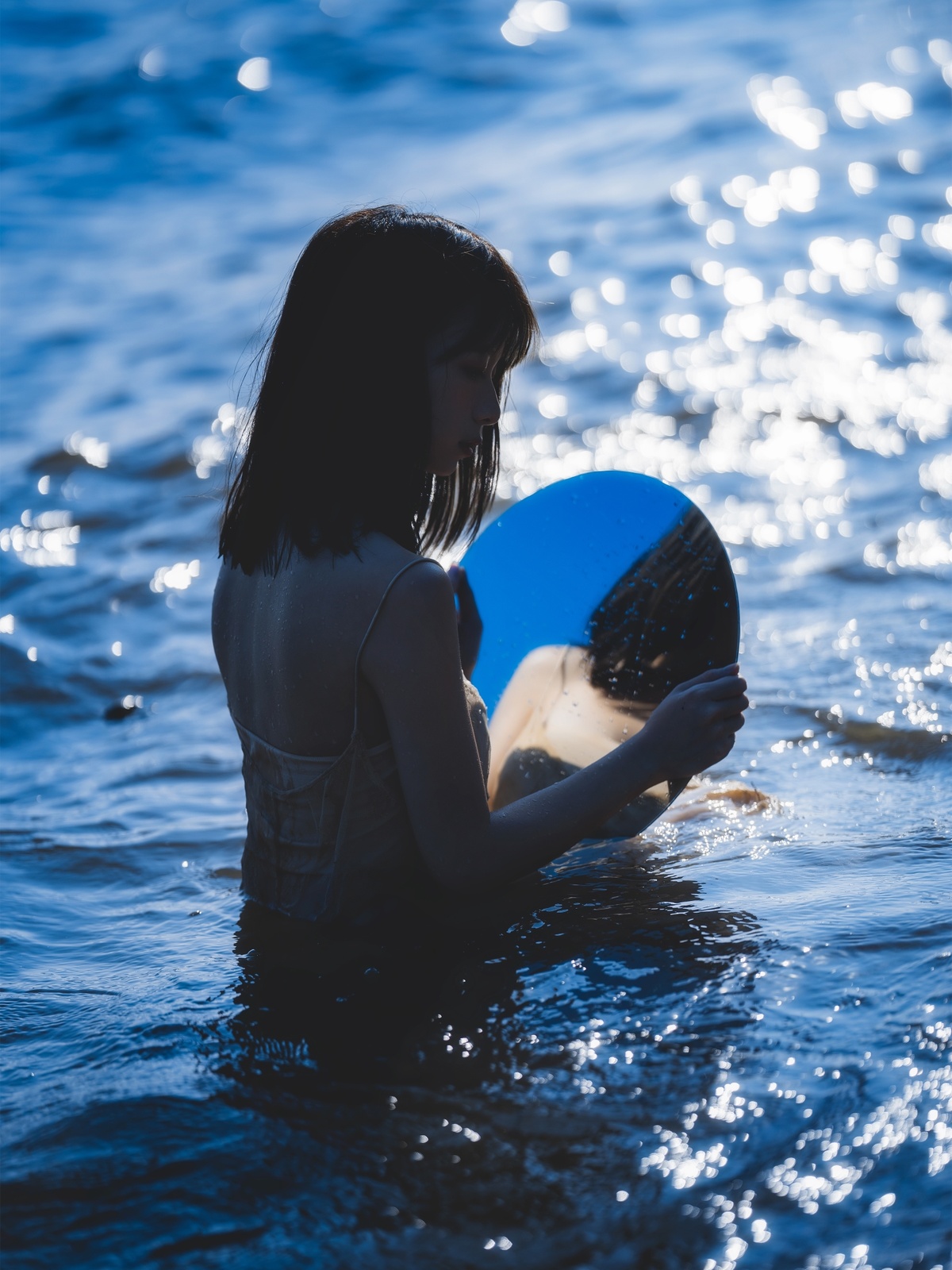 一名年轻女子在水中拿着一只蓝色飞盘