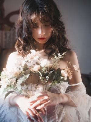 一位穿着白色连衣裙的年轻女子抱着花