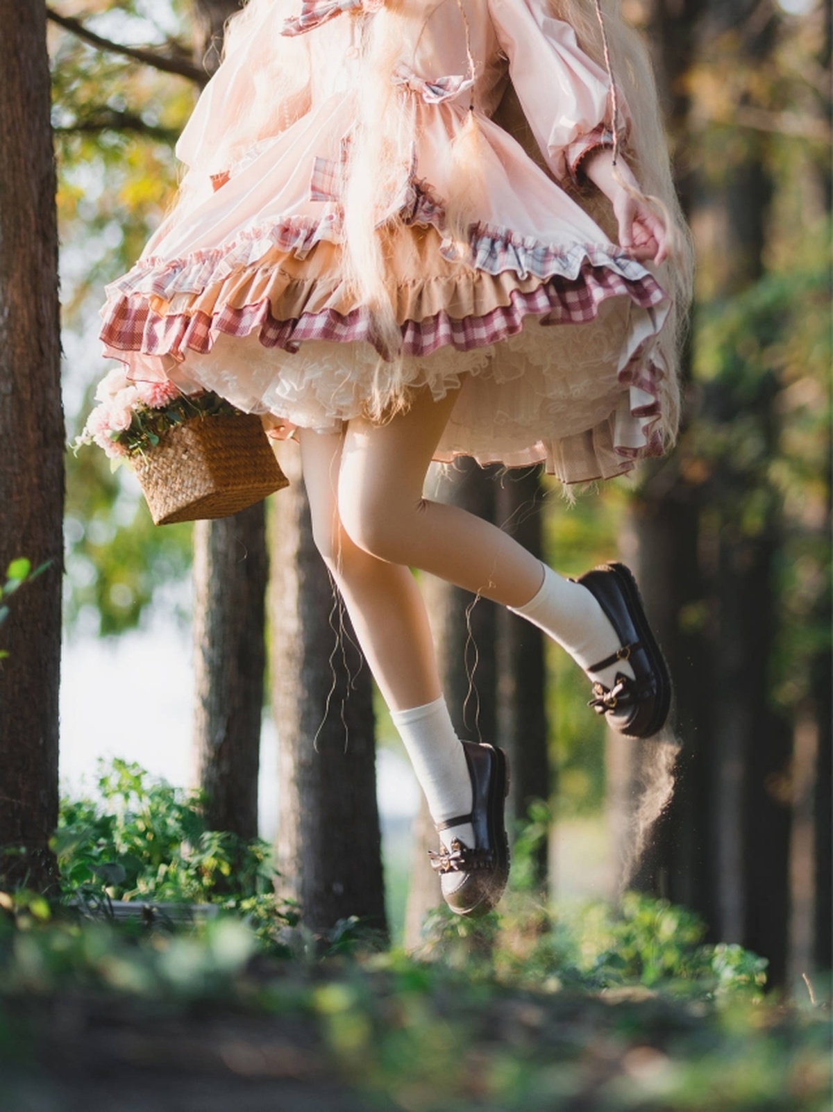 一个穿粉色裙子的年轻女孩在树林里荡秋千