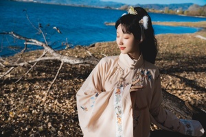 一位穿着日本传统和服的年轻女子站在湖泊边缘的岸边。