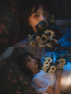 一位年轻女子抱着花躺在床上 床上有白色光线。