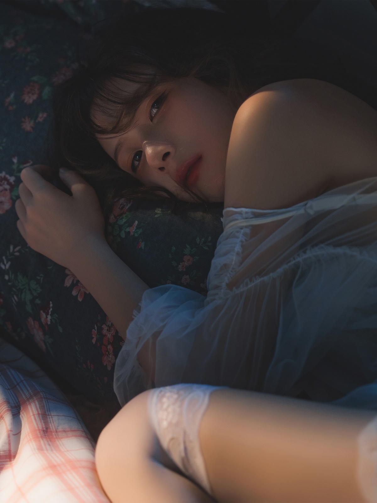 一个年轻女子躺在床上 床上有白色光线。