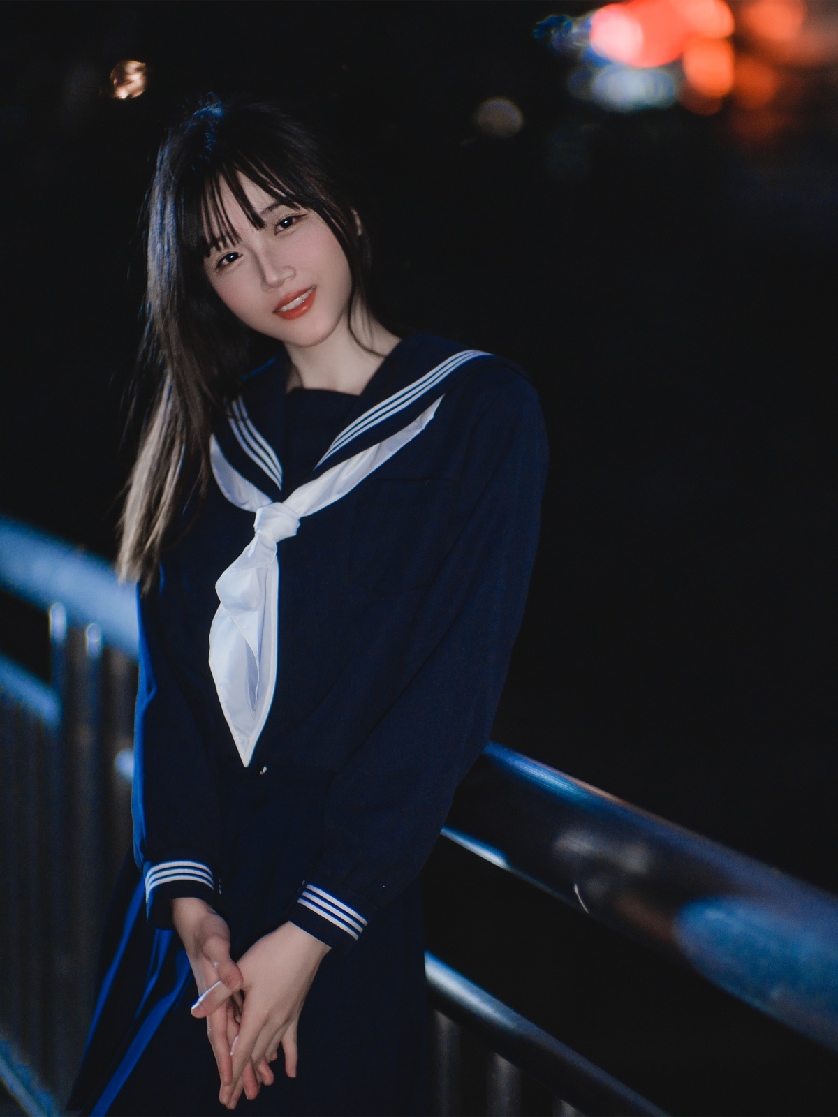 一位穿着蓝色制服的年轻女子在夜晚站在桥上。