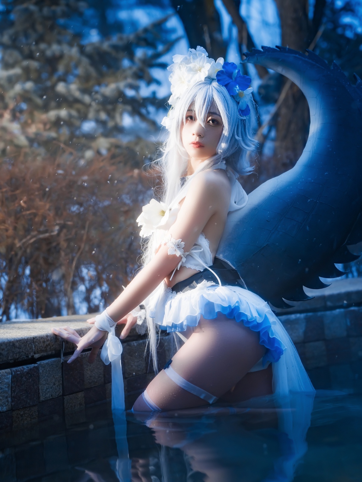 一位长着蓝色头发的美女穿着白色裙子 站在喷泉旁边。