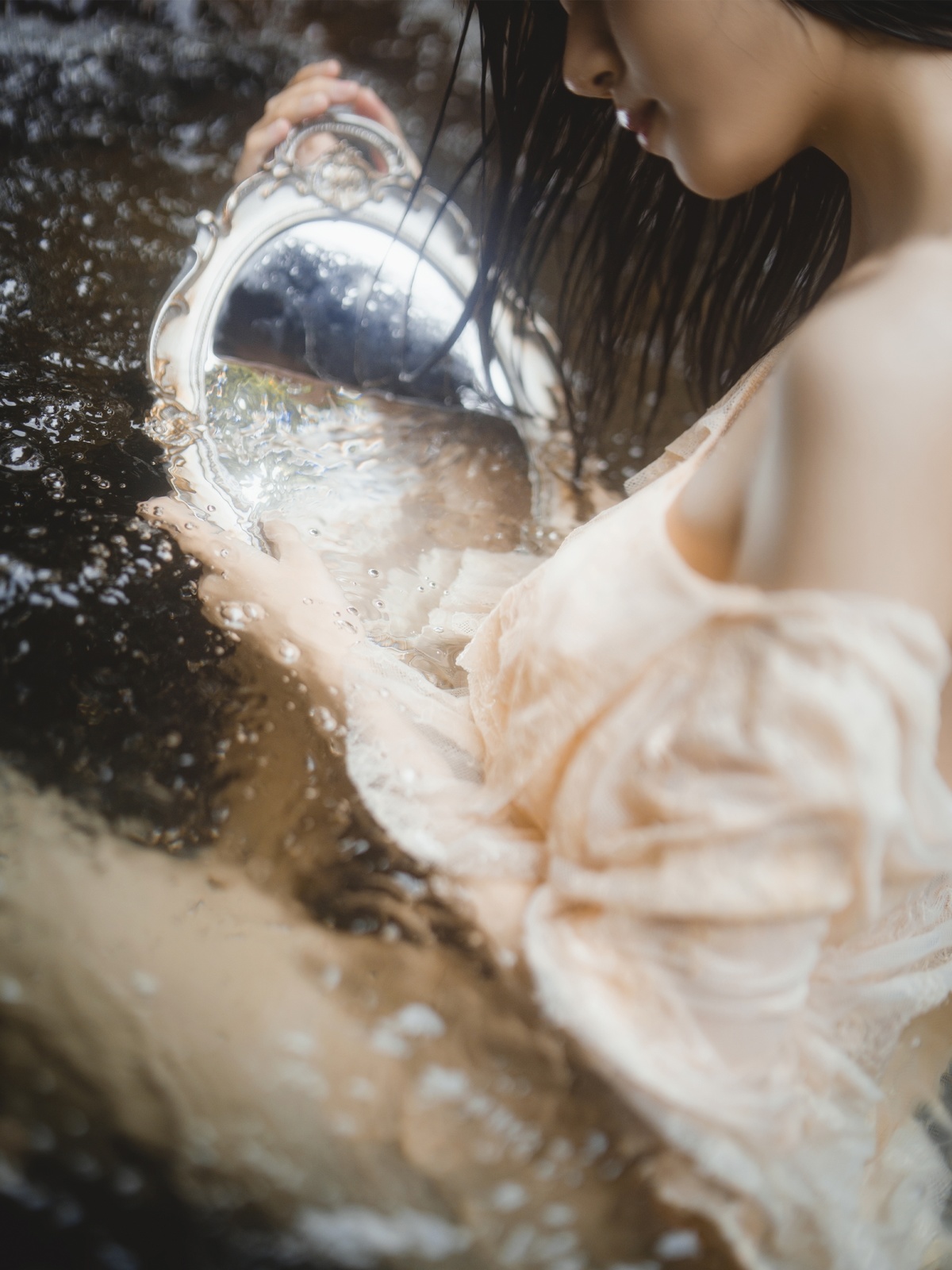一个穿银色连衣裙的年轻女子往自己身上倒水。