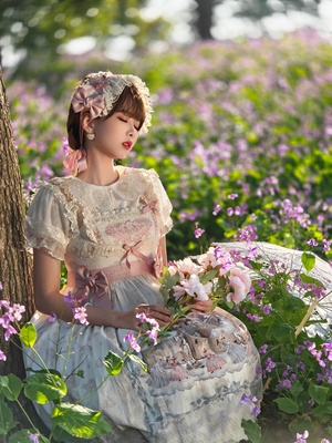 一位年轻女子穿着一件美丽的裙子 坐在一片花田中的树下。
