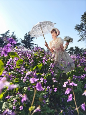 一位穿着白色连衣裙 手持白色雨伞 穿过一片紫花田地的女人