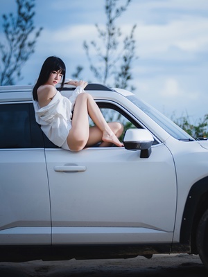 一位年轻女子坐在白色卡车上 倚靠在一条腿上