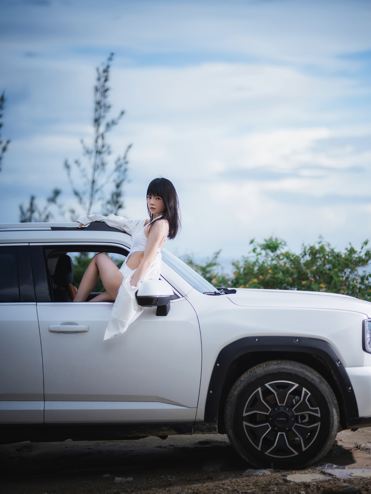 一个穿着白色连衣裙的年轻女子坐在一辆白色卡车上