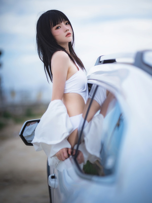 一位穿着白色连衣裙的年轻女子正在汽车窗口向外倾斜