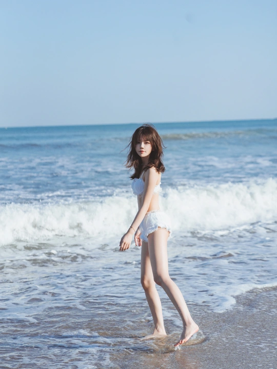 一位年轻女子在靠近海洋的海滩上行走