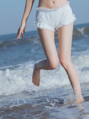 年轻女子在沙滩上跑 女孩在水里跳