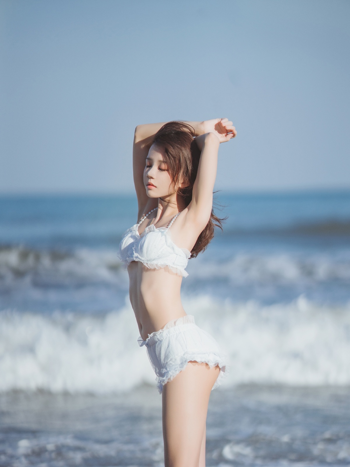 年轻美丽的女子在海洋附近的海滩上摆姿势 伸展