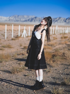 一位穿着黑色连衣裙的年轻女子站在沙漠中