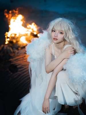一位拥有白发的年轻女子 身着白色长裙 坐在火焰熊熊的篝火前。